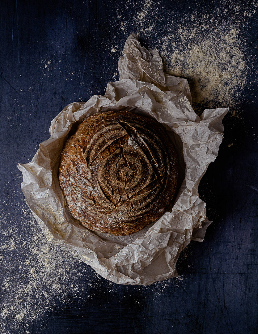 Round gluten free sourdough loaf from The Bakery by Knife & Fork on a dark background
