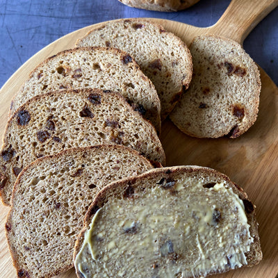 Cinnamon and date loaf, sliced and buttered on a wooden board