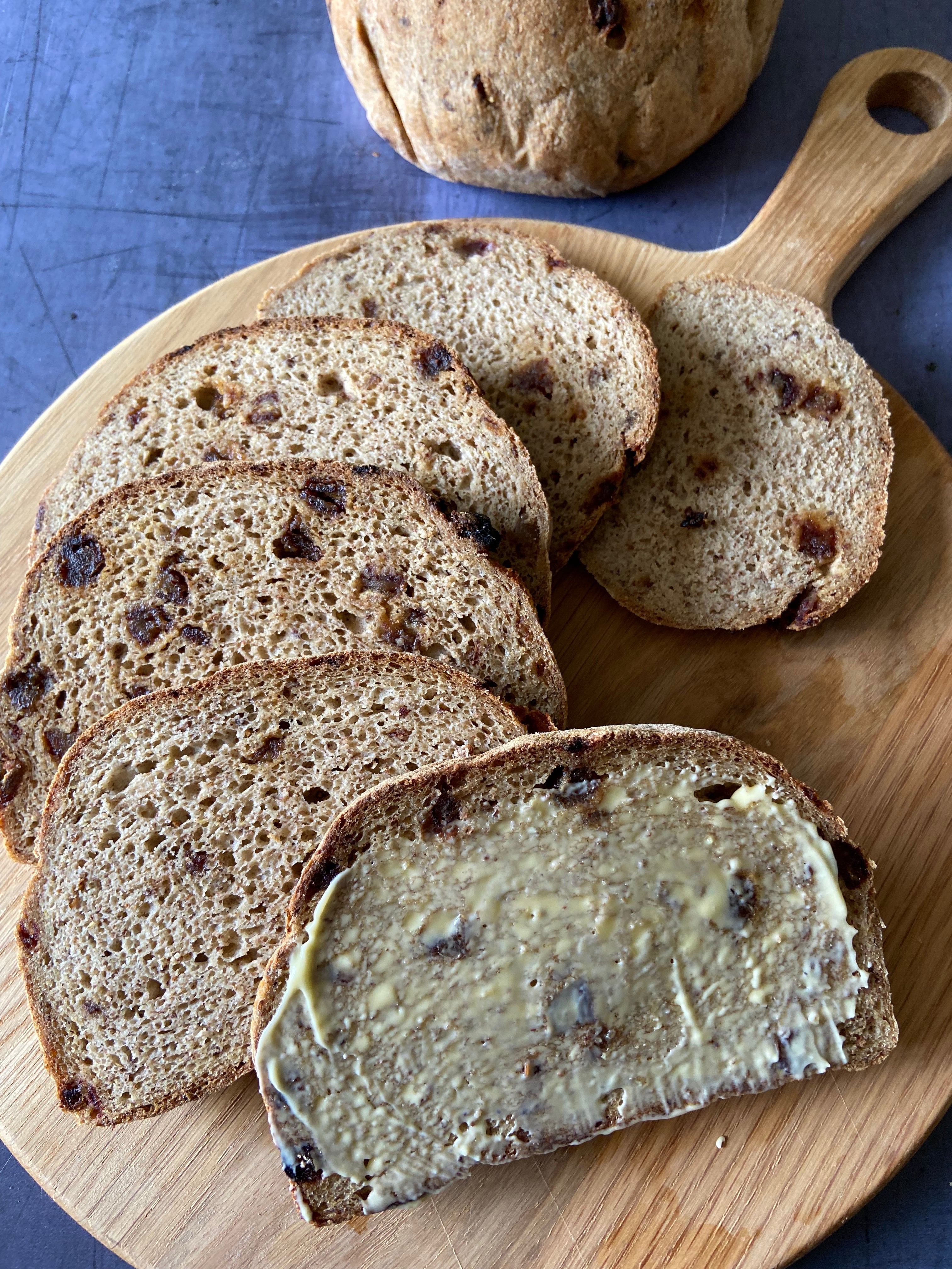 Cinnamon and date loaf, sliced and buttered on a wooden board