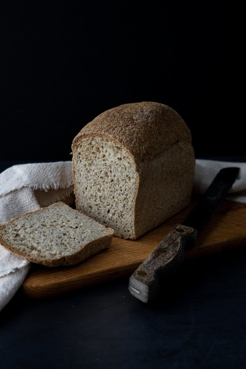 Farmhouse loaf with a slice cut, on a wooden board